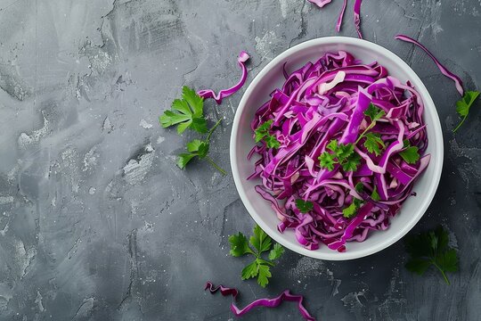 Close up top view of red cabbage salad in a bowl on a gray background