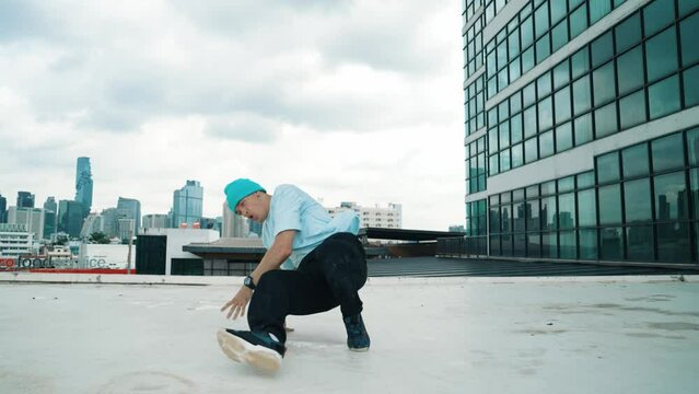 Stylish caucasian dancing man performing break dance at skyscraper. Portrait image of young happy man practicing dance performance choreographer in modern urban city. Outdoor sport 2024.. hiphop.