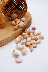 Garlic placed on a white background and some on a wooden cutting board. Food setting decor with a bamboo basket. Garlic image with rustic kitchen, cooking, and herb ingredient concept. Close-up garlic