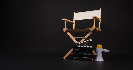 White director chair with clapper board and megaphone on black background.
