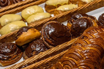 A lot of sweet pastries in baskets on the counter in the food store. Bakery on the buffet table. Business breakfasts and catering at events. Various bread type on shelf. Close-up. Selective focus.
