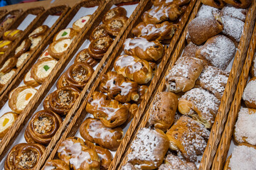 A lot of sweet pastries in baskets on the counter in the food store. Bakery on the buffet table. Business breakfasts and catering at events. Various bread type on shelf. Close-up. Selective focus.