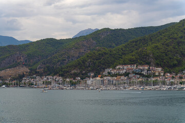View of Fethiye Bay with yachts, houses, mountains on a cloudy day, Turkey