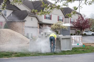 Construction Worker Sawing Cement Block in Cloud of Dust