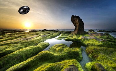 Illustration of a stark landscape with a sun setting and a UFO in the sky above. - 782377119