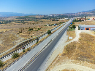 Top view of an asphalt road with cars, fields, mountains near the town on a sunny day, Turkey.