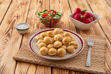 Fried dumplings in a plate, radishes and fresh vegetable salad