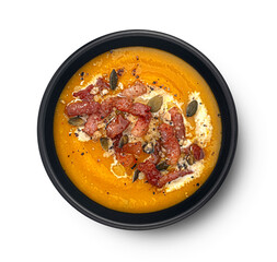 Pumpkin cream soup with crispy bacon isolated on white background, top view