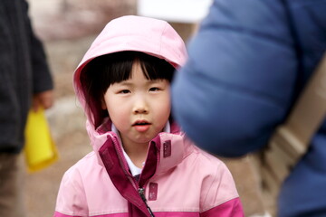 An Asian girl is smiling when parents pick up her.