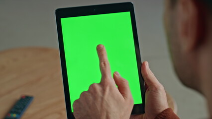 Guy finger touching greenscreen tablet at office room. Man using chroma key tab