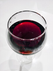 A glass of wine with parmesan cheese and olives. Natural wine in a glass on the kitchen table. Alcoholic drink red.