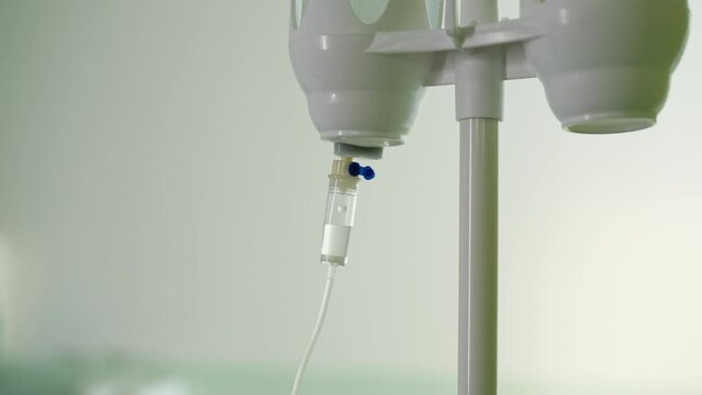 Closeup view of IV drip in hospital. Close-up of intravenous saline solution in medical clinic in light bright interior. Saline solution drip for patient in hospital, no people, nobody, slow motion.