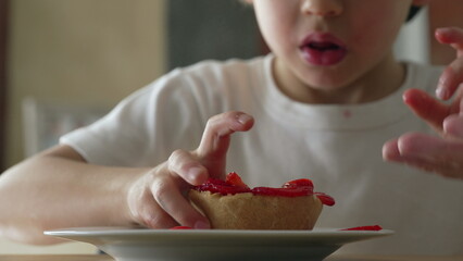 One small boy savoring cheesecake dessert. 5 year old child grabbing sugary food from plate