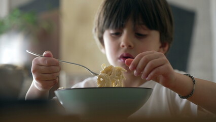 Spaghetti delight - Little boy attempting to spin fork while eating pasta food during mealtime....
