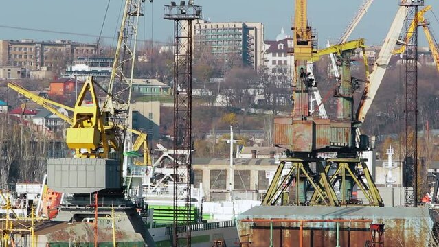 Historic Azov shipyard in Mariupol showcases sprawling docks, towering cranes, maritime construction. Clip reveals industrial vessel assembly, heavy machinery, urban backdrop economic vigor.