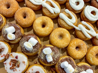 A box of special donuts topped with icing, marshmallows, and nuts