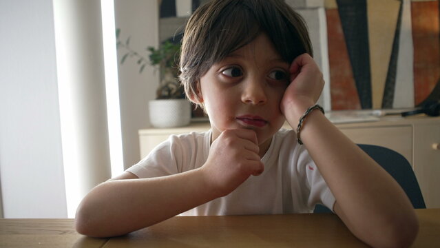 Pensive small boy pondering solution to a problem, close-up face of one handsome caucasian 5 year old kif with hand in chin with thoughtful expression
