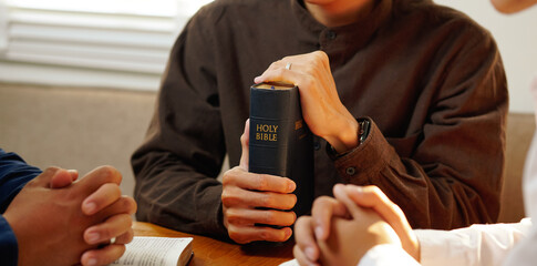 Man is sitting and holding hand for pray, read holy bible and worship jesus christ in the morning...