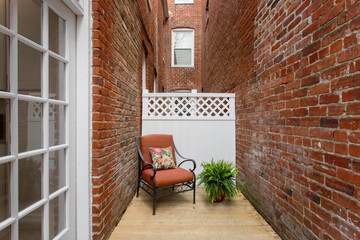 Cozy Narrow Patio Chair Between Brick Walls, Historic Row Homes Exterior