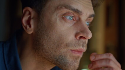 Focused man staring screen at night flat closeup. Guy hands typing keyboard