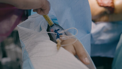 Close up hands doctor nurse inject iv anesthesia in catheter intravenously anesthetic drug syringe...