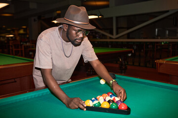 Waist up portrait of Black young man playing pool in underground club shot with flash copy space - 782440167
