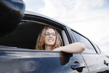 young beautiful smiling woman in car looking somewhere while traveling, attractive caucasian woman...
