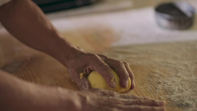 Hands take the portion of raw wheat flour dough to shape it and make bread.