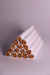 a group of white cigarettes with gold tobacco in the shape of a pyramid on a white background