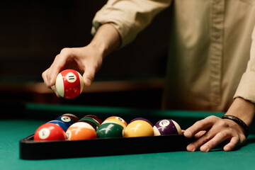 Close up of male hand holding red billiards ball over pool table in low light copy space - 782452952