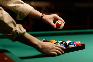Minimal side view closeup of male hands setting up billiard balls on pool table copy space