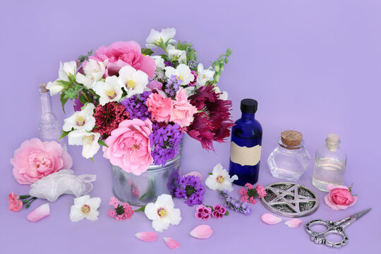 Flowers and herbs preparation for herbal remedies. Flower essences with quartz crystal for alternative medicine on lilac background. Wicca occult natural medicinal healing concept.