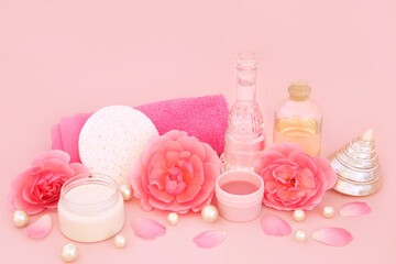 Rose flower health spa beauty treatment products on pink. Natural feminine healthcare for sensitive skin, with moisturizer, aromatherapy oil, scrub, rosewater, shells, pearls and flowers.