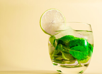 Mojito with a straw in a glass. Summer mint drink with a lime wedge. Soda in a transparent glass. Alcoholic drink Apperol. Natural juice with ice.