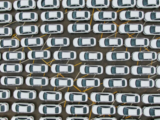A large parking lot full of white cars. Cars leaving the car factory are waiting at the port for sale and transportation. © FATIR29