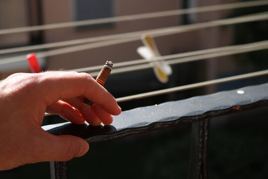 Smoking cigar on balcony man hand close up 