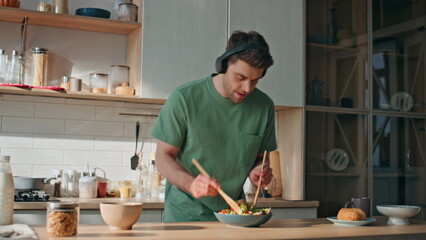 Guy earphones preparing food dancing along favorite song at kitchen closeup