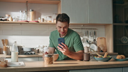 Happy man reading cellphone message kitchen counter closeup. Businessman eating