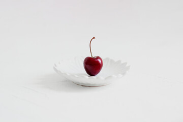 Cherries on a bowl, on white background. Minimalist composition.