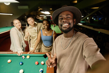 Waist up portrait of African American man taking selfie photo with diverse group of friend in pool club - 782461184