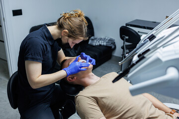 Modern dental equipment. The orthodontist installs the bracket system on the patient's teeth,...