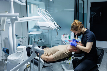 Modern stomatological office. An orthodontist installs braces. Treatment of teeth of a person with an incorrect bite. Treatment of teeth