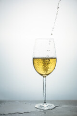 clear crystal glass of white wine pouring wine from the bottle with the table full of liquid