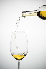 white wine glass with bottle pouring the liquid on a light background