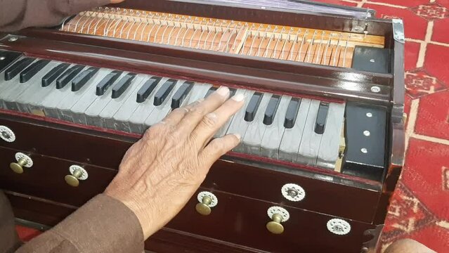 A Man Playing Harmonium. Closeup shot of hands of a Man playing Harmonium. Traditional world. Folk instrument. Pakistani man playing harmonium in the house. Beautiful 4K Footage.