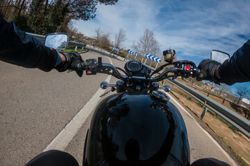Riding a motorbike with a black fuel tank on a left turn asphalt road rider point of view