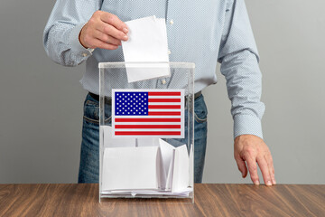 A voter casts a ballot into a ballot box on election day, USA flag