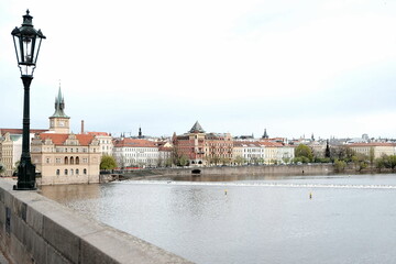 Blick von der Karlsbr&uuml;cke mit alter Stra&szlig;enlaterne auf die Moldau und die Altstadt von Prag mit Altst&auml;dter Wasserturm und Bedrich Smetana Museum mit Wolken bei Regenwetter im Fr&uuml;hling in Tschechien
