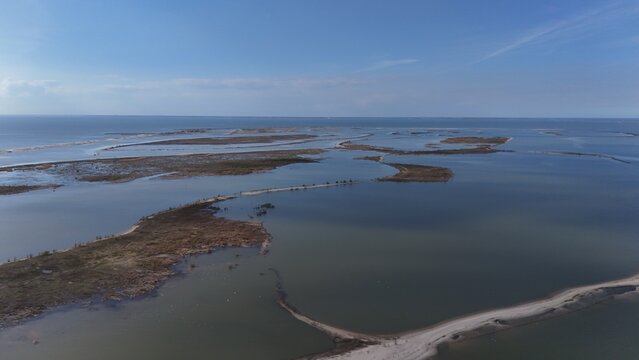 Aerial view of a tranquil coastal wetland with scattered islands, serene waterways, and diverse vegetation under a clear sky, showcasing a natural habitat and peaceful scenery.