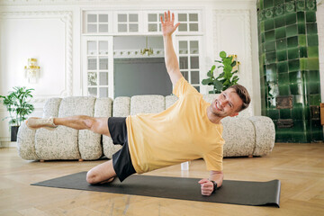 Man performing an advanced side plank exercise, demonstrating balance and core strength in a spacious living area.